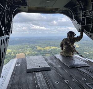 Four Winds Aerial founder Tim Wilkins sitting on back of in flight military aircraft